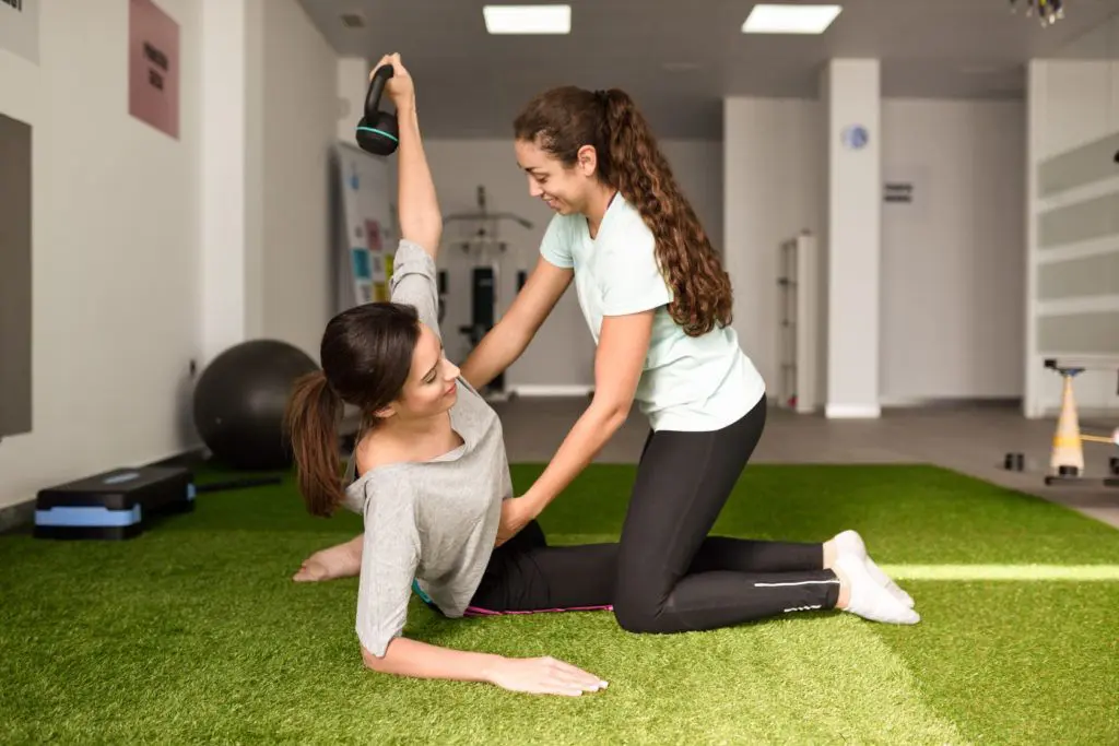 Physiotherapeutin mit Patentin bei Übungen am Gerät mit Hantel während der Rehabilitation im Physiotherapiezentrum in Kappeln.