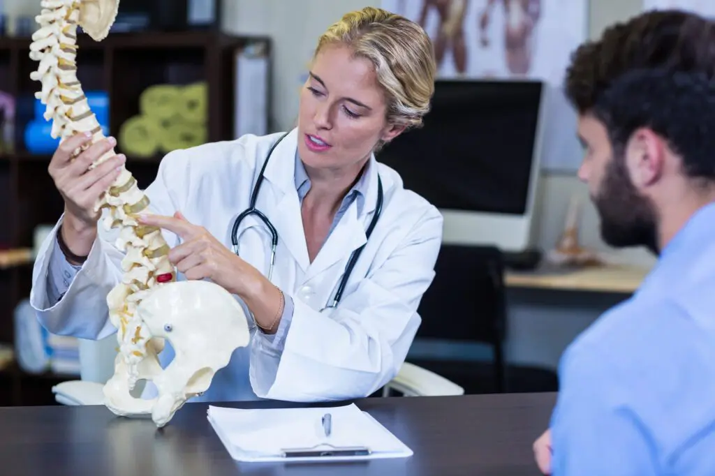 Physiotherapeut erklärt dem Patienten das Wirbelsäulenmodell