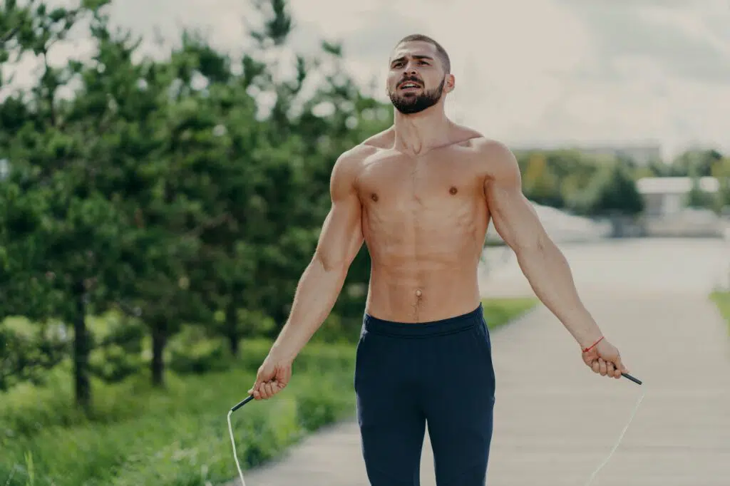 Athletic motivated man with naked torso concentrated on intense fitness training program.