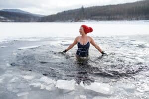 Kältetherapie - Front view of active senior woman in swimsuit outdoors in winter, cold therapy concept