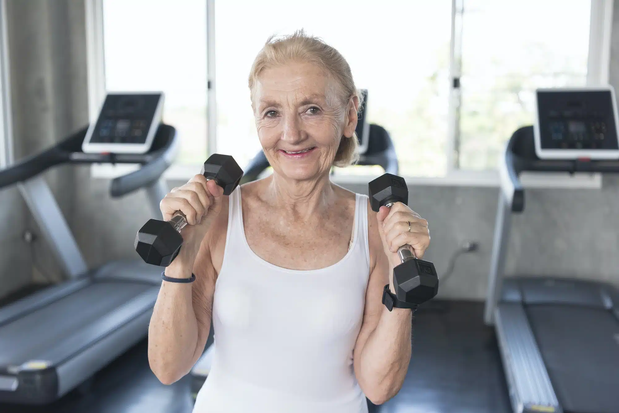 Senior woman exercise lifting dumbbell in fitness gym.