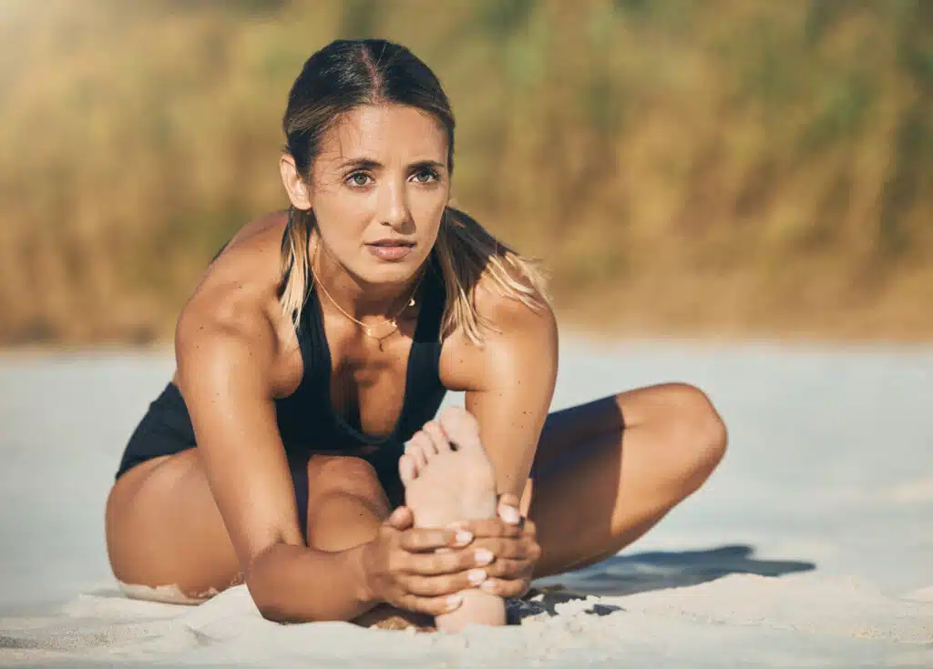 Die besten Übungen für die Beweglichkeit der Hüfte: Frau macht einen entspanntem Workout am Natur-Sandstrand an der Schlei