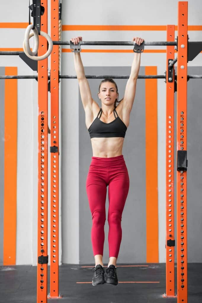 Schulterverspannungen in 5 Minuten beseitigen 2 achte Fitte, sportliche Frau, die in einem Crossfit-Fitnessstudio einen Dead Hang macht