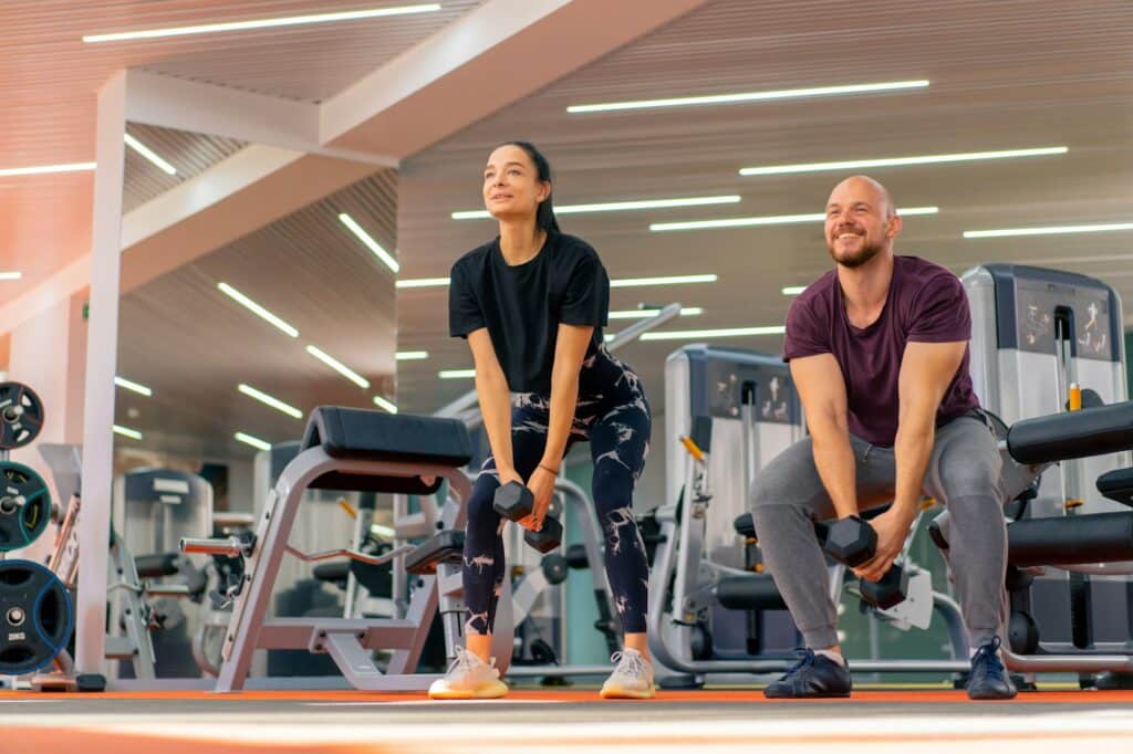 Die Kraft der täglichen Bewegung 2 bewegung girl fitness trainer and bodybuilder doing exercises with dumbbells in the gym group training