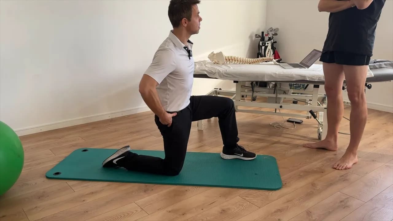 Golf Physiotherapie: Wie gezielte Physiotherapie deinen Golfschwung verbessert 1 Golfphysiotherapie Therapeut demonstriert kniende Quadrizeps-Dehnung auf Matte, Hand am Becken zur Kontrolle der Beckenstellung